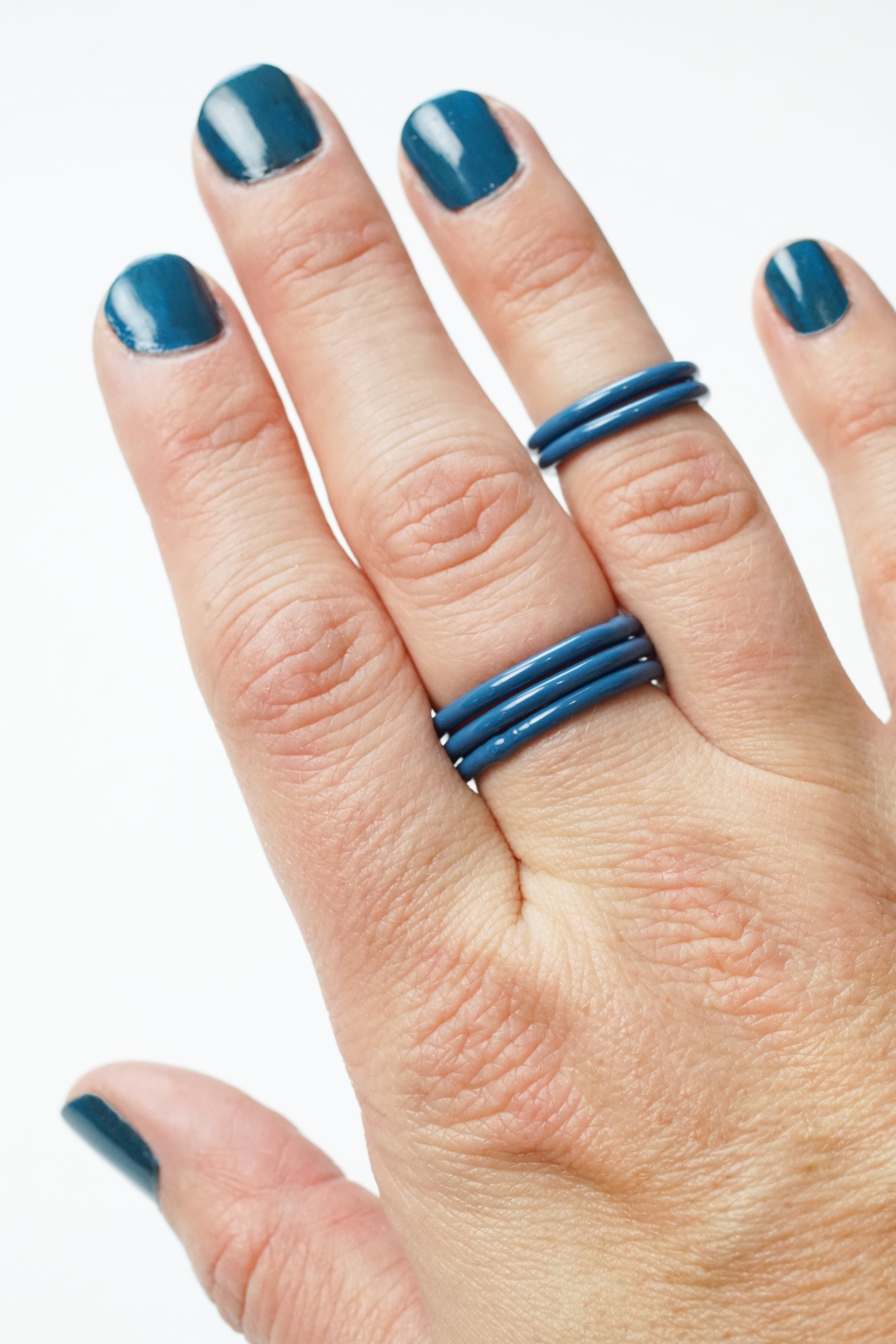 hand wearing azure blue stacking rings and matching nail polish